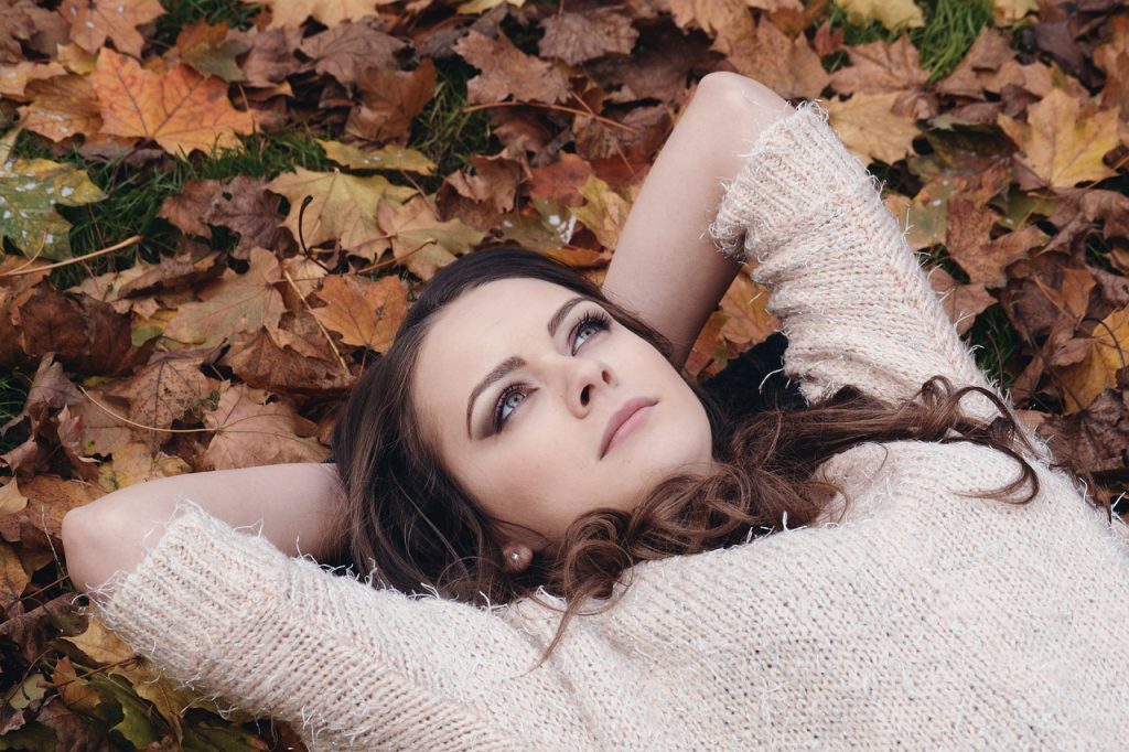 mulher deitada no chão no meio das folhas