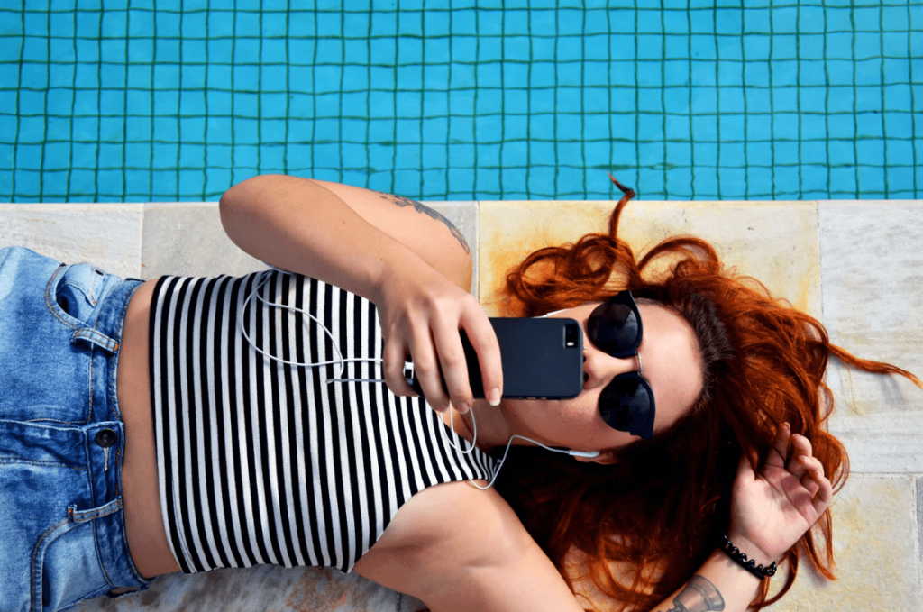 mulher deitada na piscina mexendo no celular trocando o status das redes sociais