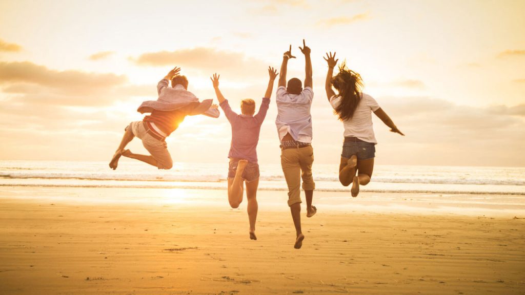 quatro amigos felizes pulando e se divertindo na praia