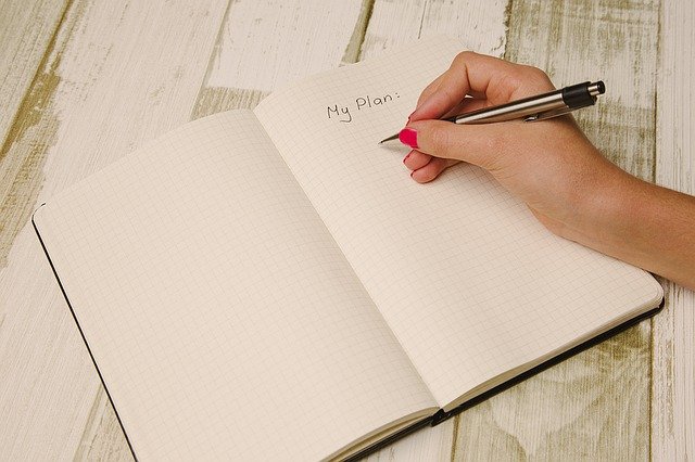 pessoa escrevendo com caneta no caderno