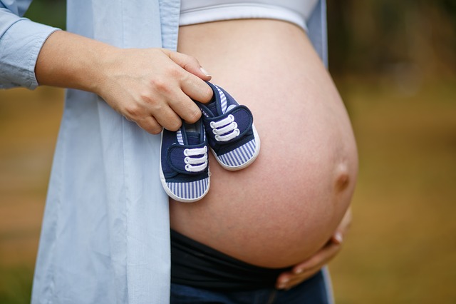 mulher grávida com sapatinho de bebê na mão